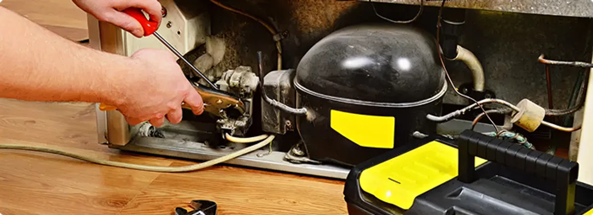 Refrigerator repair technician fixing the compressor and wiring in Arvada, CO